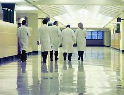 Gruppo di medici ritratti di spalle mentre attraversano il corridoio di un ospedale