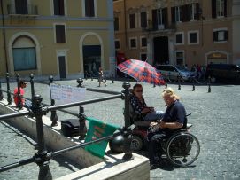 Un ombrello protegge Lorenzo Milano dal sole, davanti a Palazzo Montecitorio, in compagnia di un amico