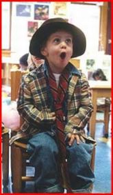 Bambino seduto in un'aula, con il cappello e la bocca aperta