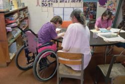 Alunna con disabilità a scuola insieme a un'assistente