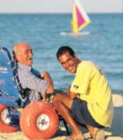Persona con disabilità in spiaggia insieme a persona non disabile